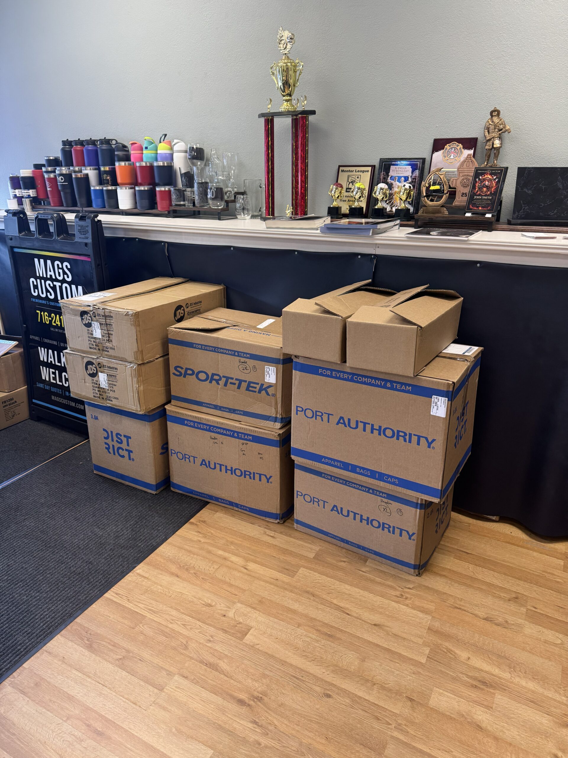 Boxes of District and Sport-Tek apparel ready for the Whippo Trucking custom apparel order