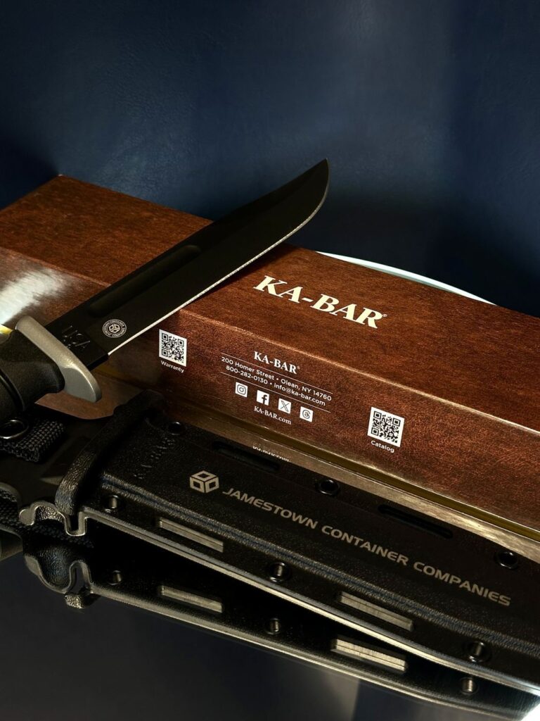 KA-BAR knife resting on its wooden box with the Jamestown Container Companies laser-engraved sheath below