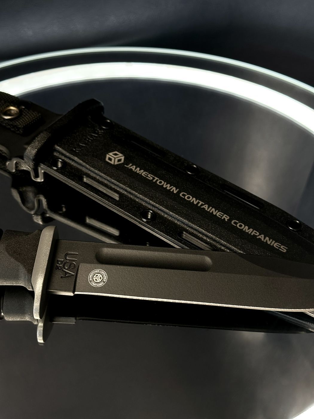Close-up of the KA-BAR sheath with Jamestown Container Companies logo and name laser engraved in white text