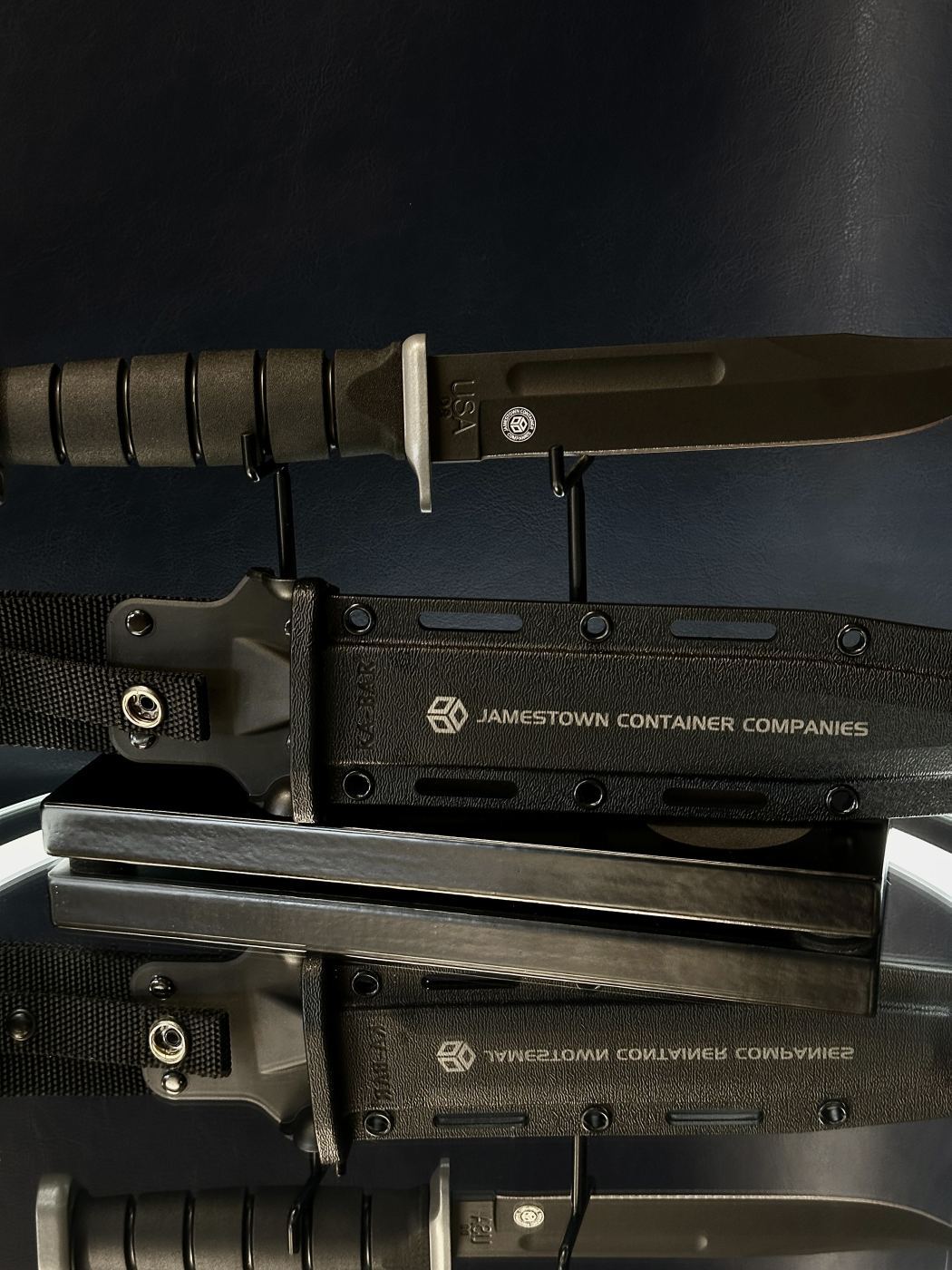 Two laser-engraved KA-BAR sheaths for Jamestown Container Companies displayed with the knife above